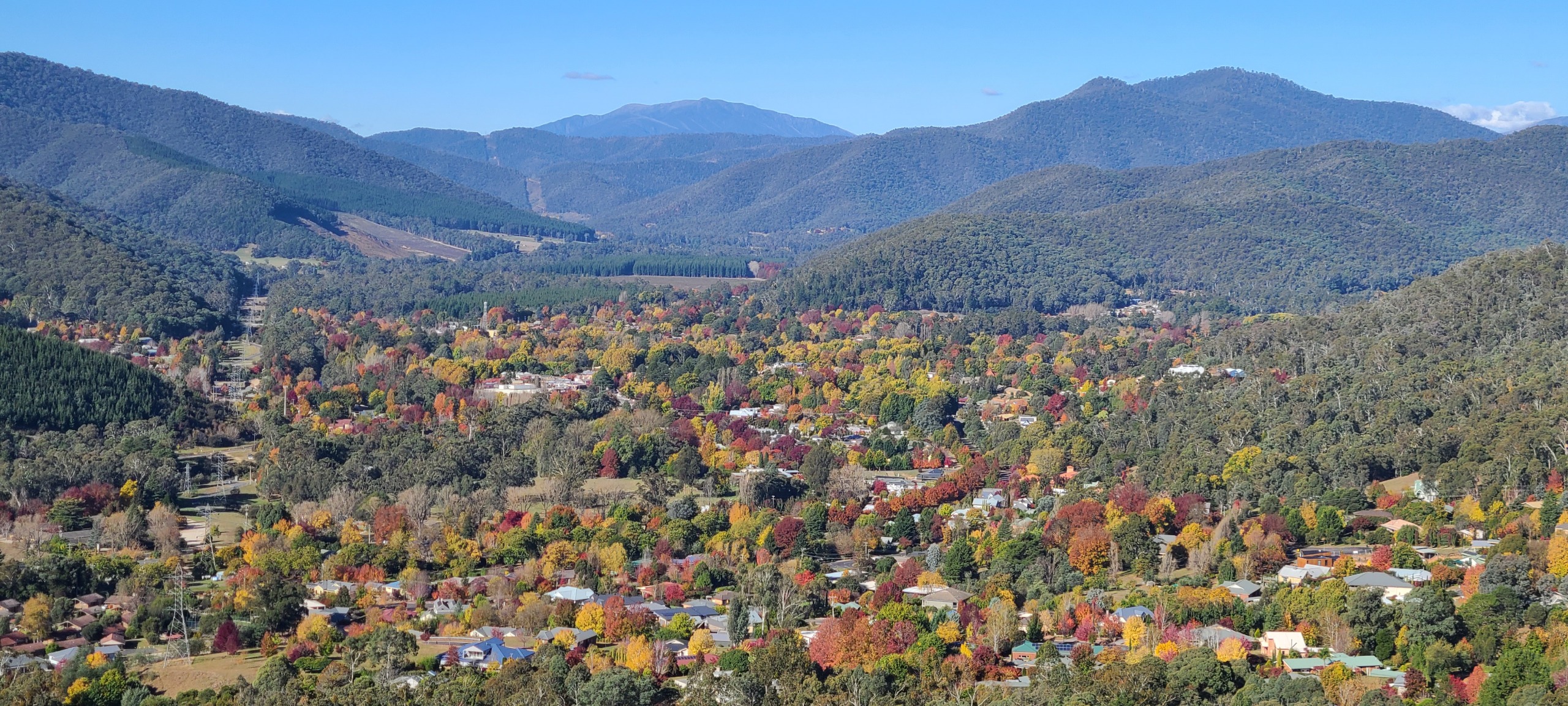 An overhead shot of a town in summer with small mountains in the background.