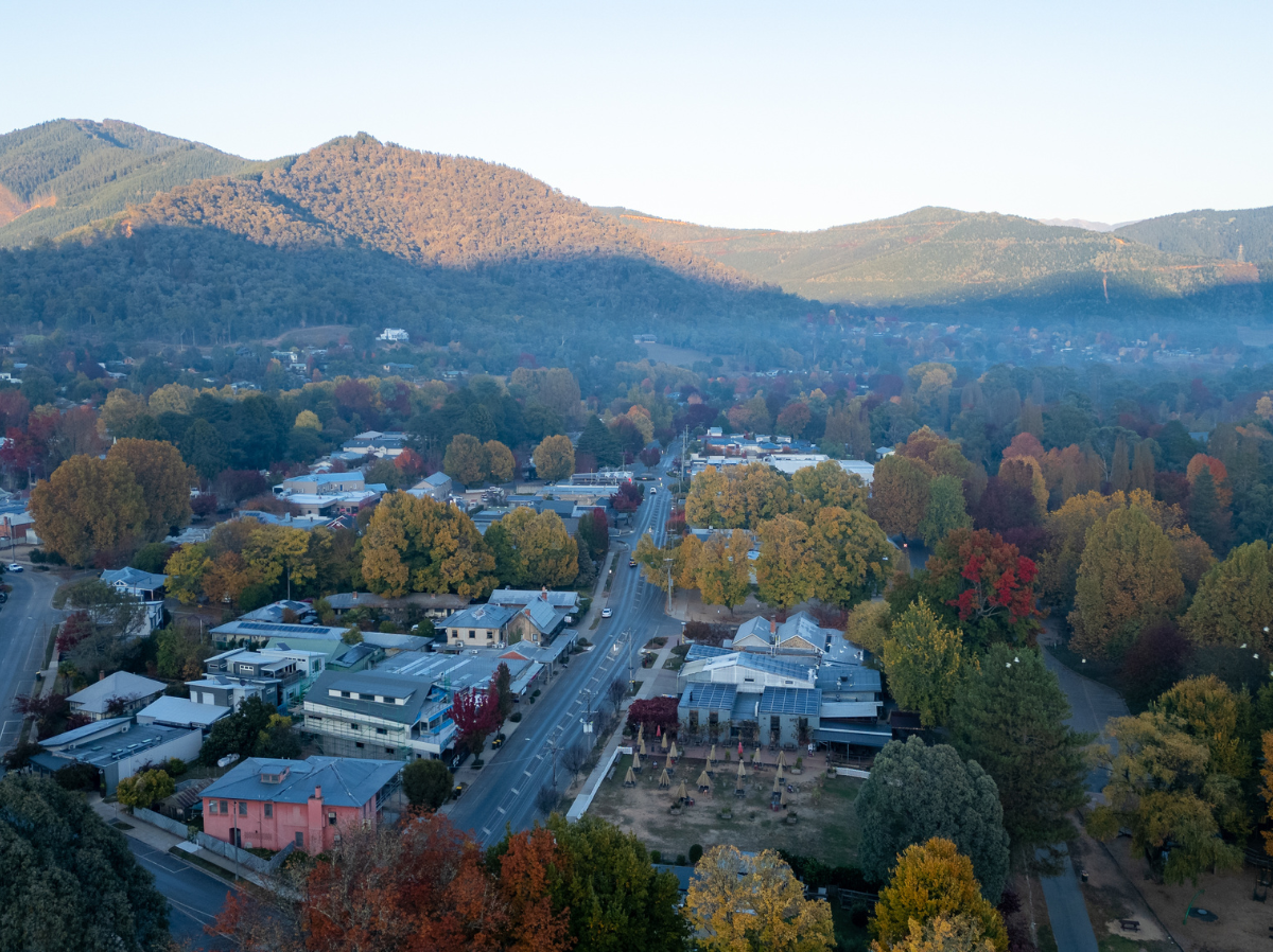 A rural town with the sun setting on the hills behind.